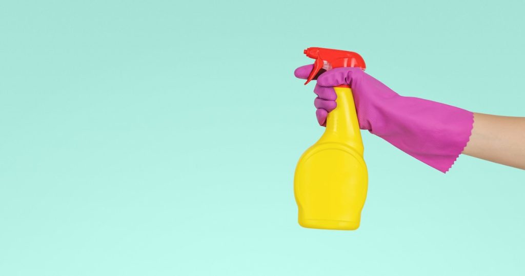 person holding yellow plastic spray bottle