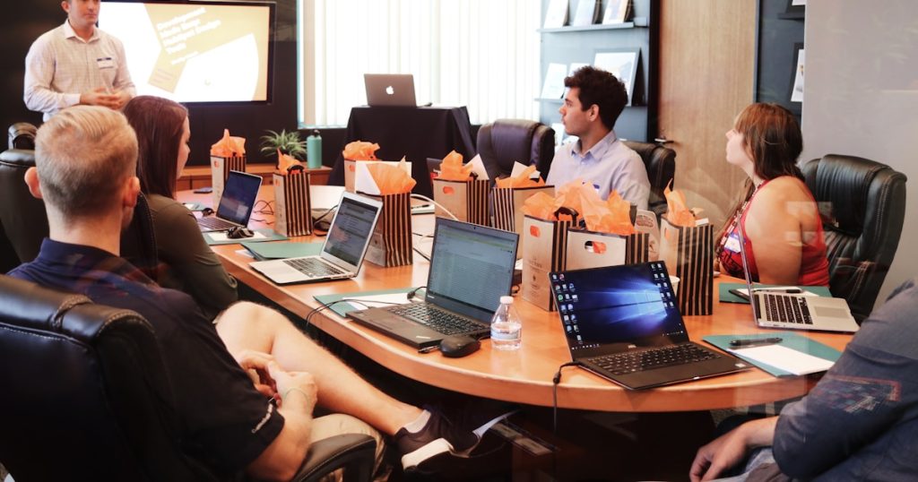 man standing in front of people sitting beside table with laptop computers