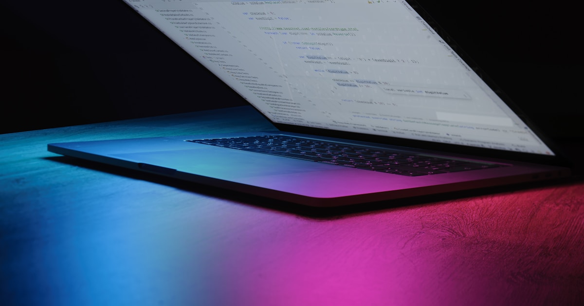 Open laptop with code on screen, neon lighting