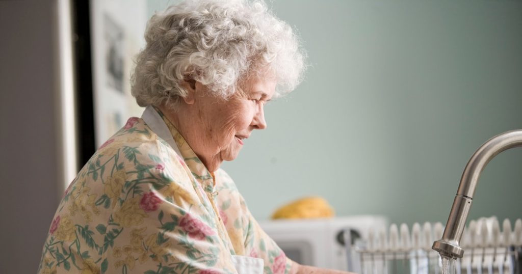 woman in yellow and green floral shirt holding white ceramic mug