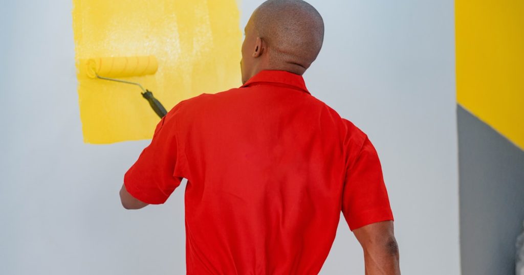 a man painting a wall with yellow paint