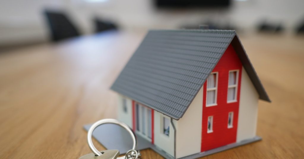 white and red wooden house miniature on brown table