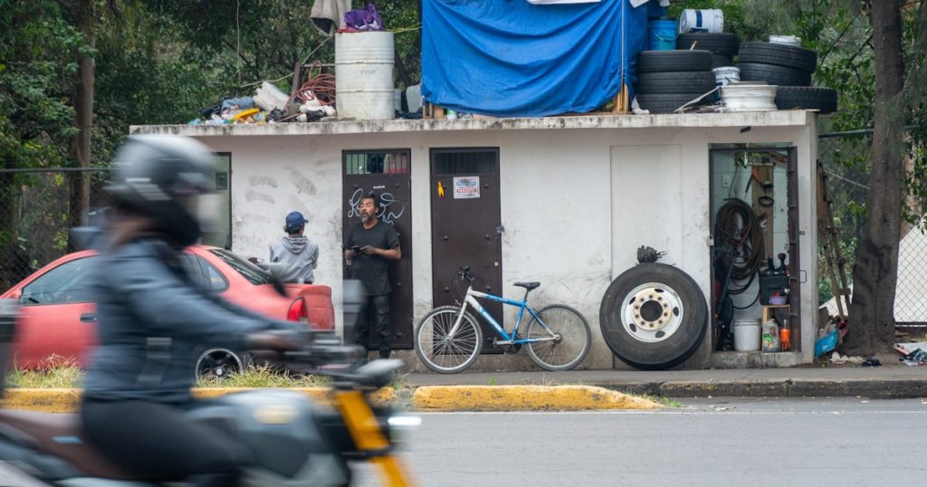 Small makeshift structure with tires and blue tarp.