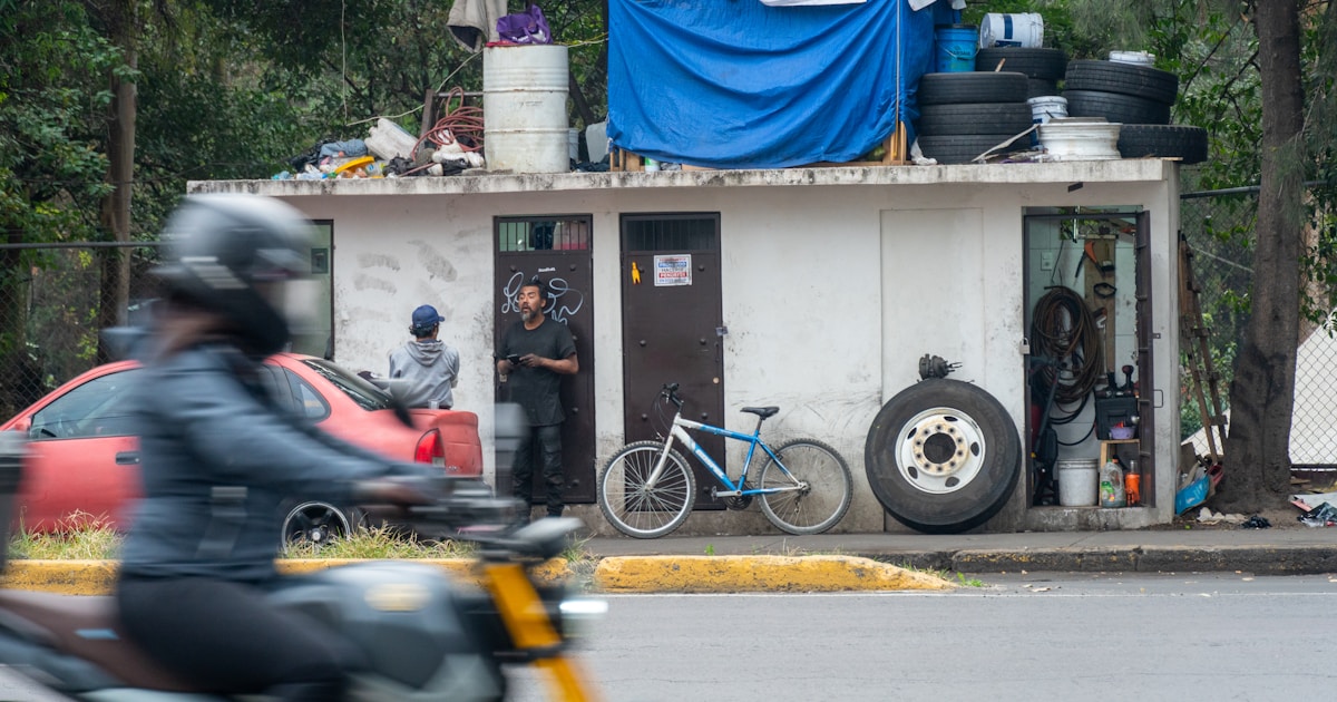 Small makeshift structure with tires and blue tarp.