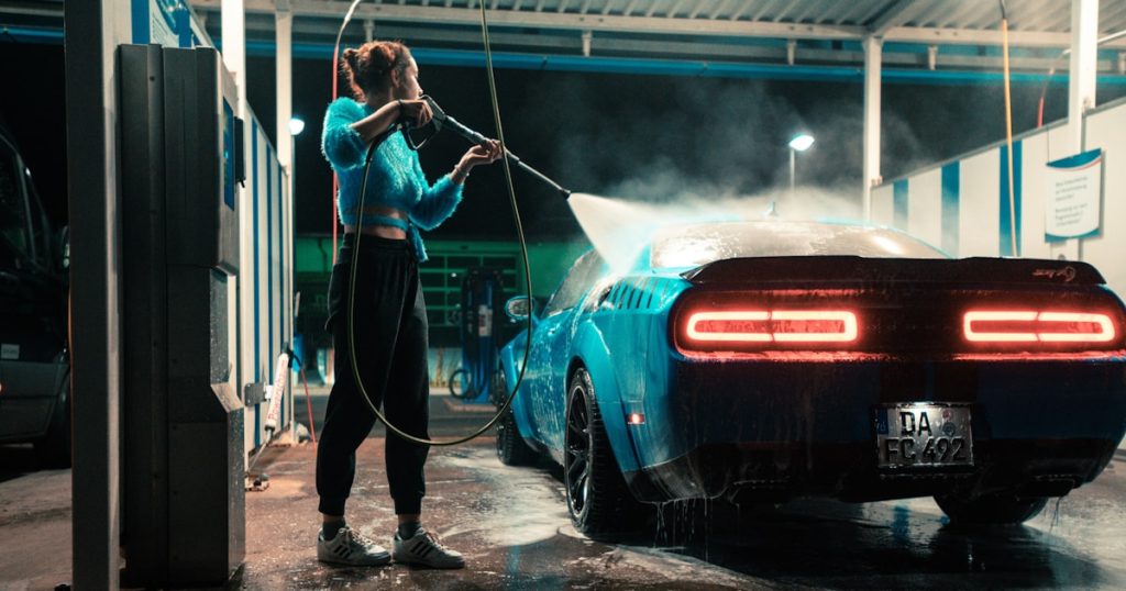 a woman washing a car with a hose
