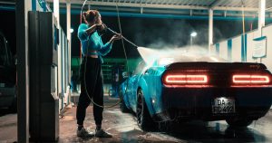 a woman washing a car with a hose