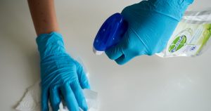 person in blue gloves holding white textile