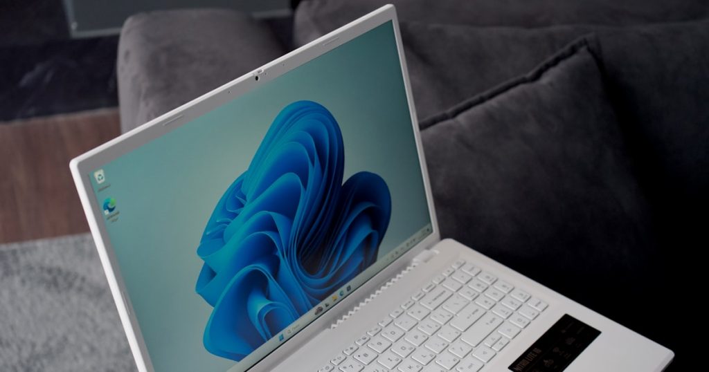 A white laptop with a blue windows 11 wallpaper.