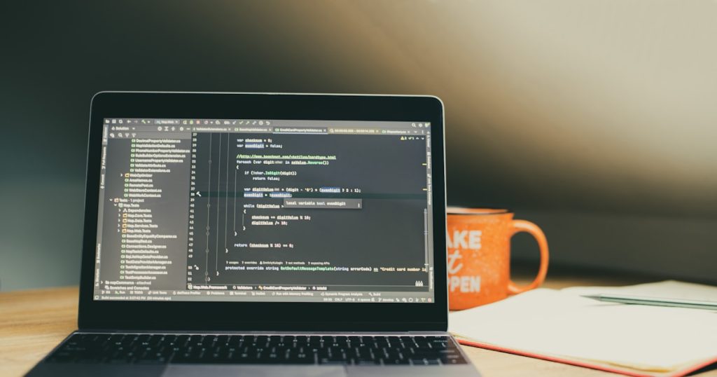 Laptop displaying code with an orange mug nearby