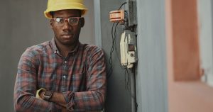 man in blue white and red plaid button up shirt wearing yellow hard hat holding black