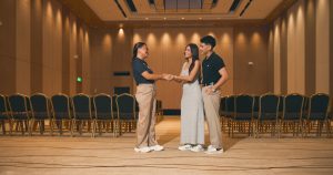 Three people standing in an empty conference room.