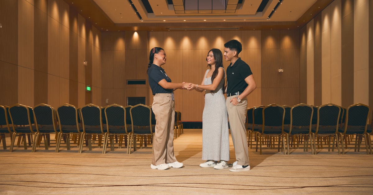 Three people standing in an empty conference room.