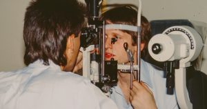 Optometrist examining a patient's eye with equipment.