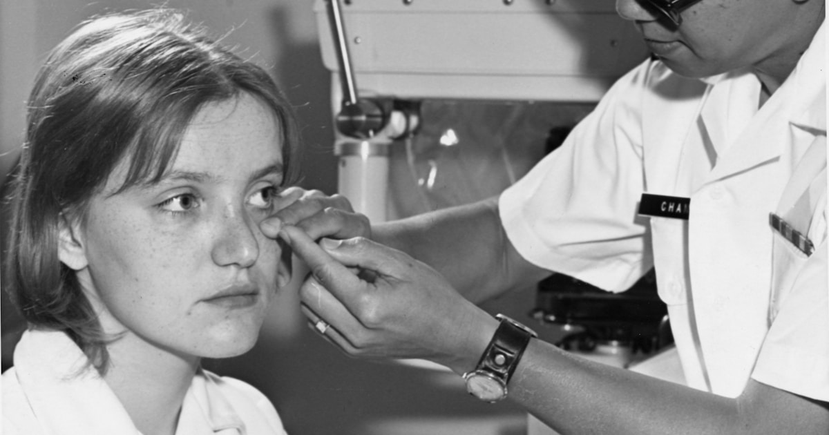 Doctor examines a woman's eye with equipment.