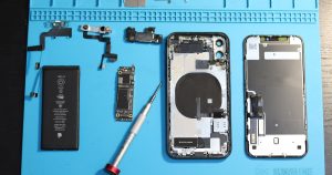 iPhone components are disassembled on a blue mat.