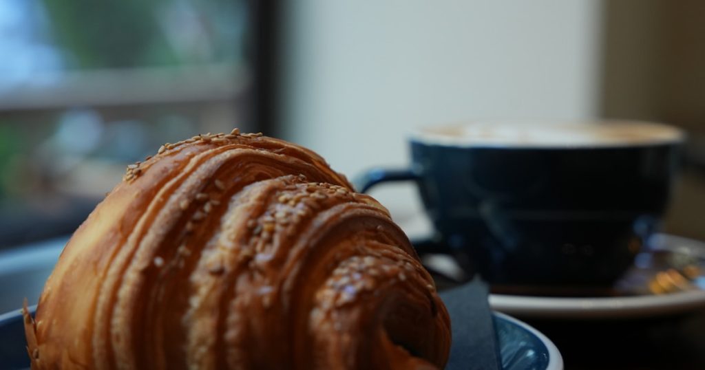 A croissant and a cup of coffee on a table