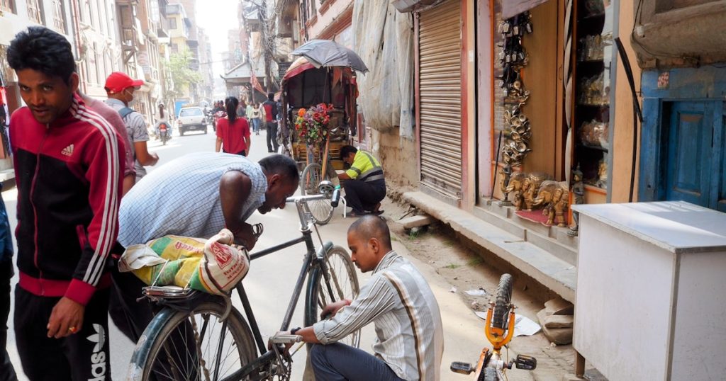 Men repairing a bicycle on a street.