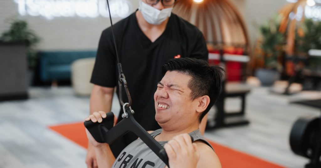 Man straining while doing a cable pull exercise.