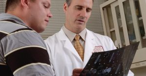 man in white dress shirt holding black tablet computer