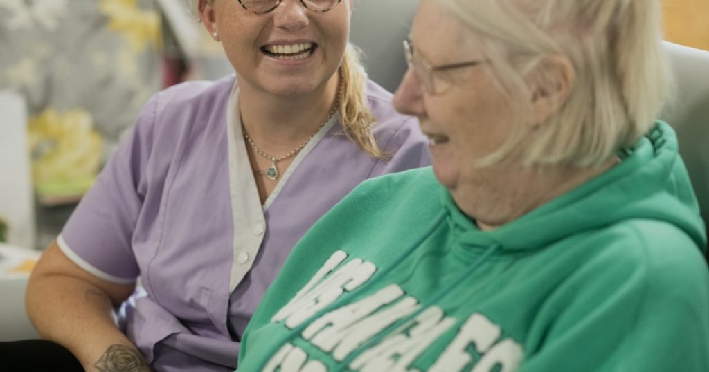 Two women laughing together indoors.