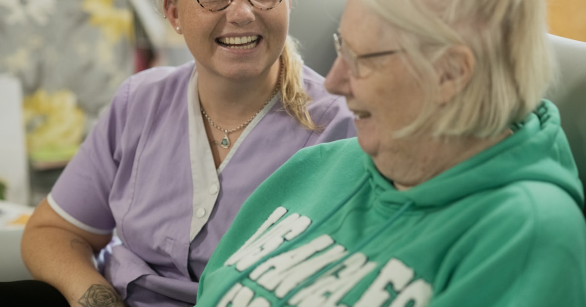 Two women laughing together indoors.