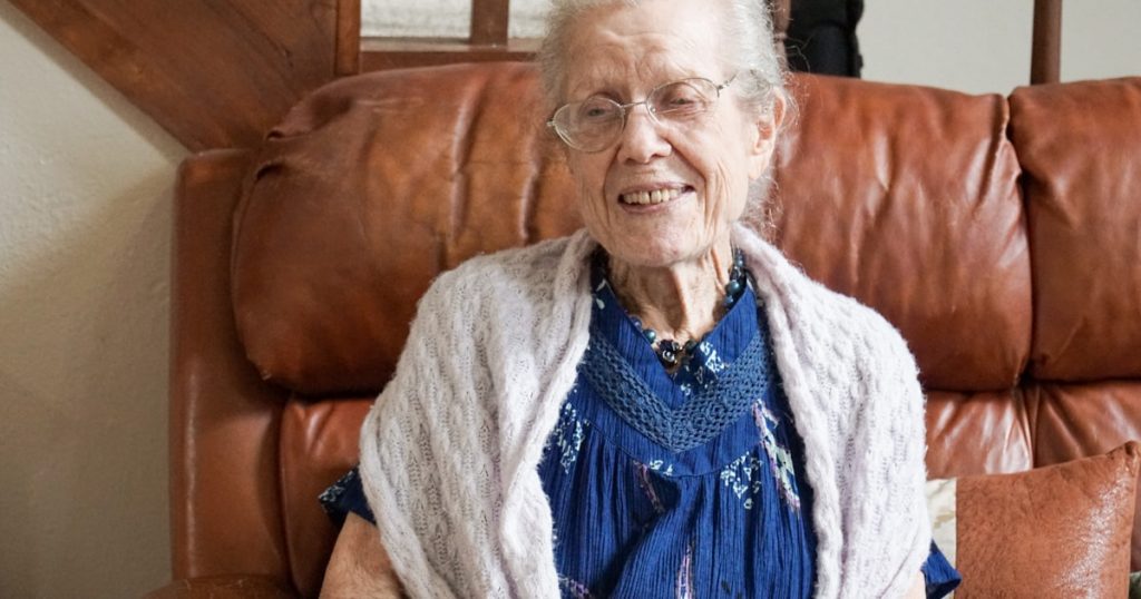 woman in blue shirt and gray cardigan sitting on brown sofa