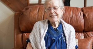 woman in blue shirt and gray cardigan sitting on brown sofa