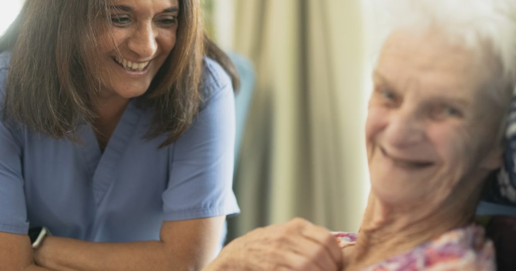 Nurse smiling with elderly patient in room