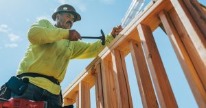 a man in a hard hat and safety gear working on a wooden structure