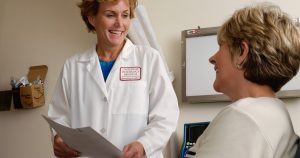 woman in white scrub suit holding gray laptop computer