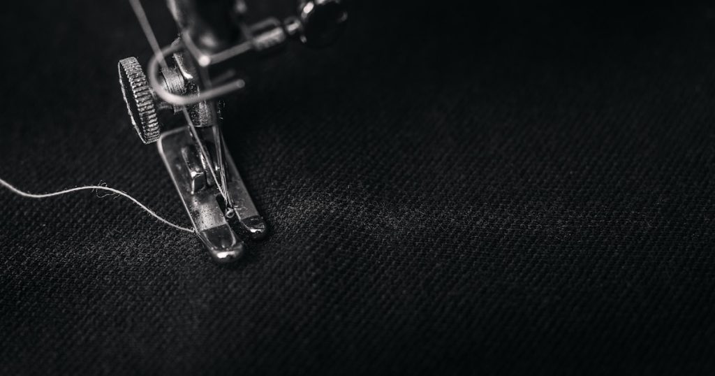 photo of gray sewing machine foot lock with thread on black cloth