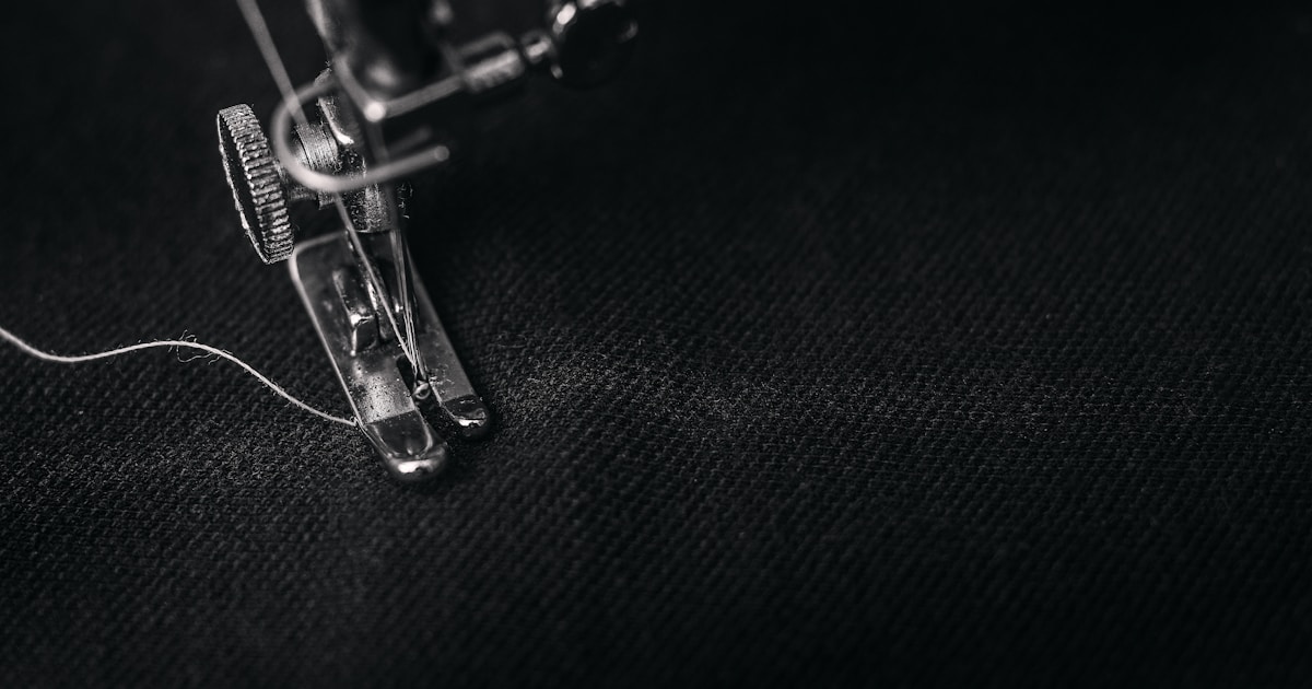 photo of gray sewing machine foot lock with thread on black cloth