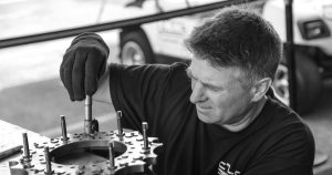 grayscale photo of man fixing gear