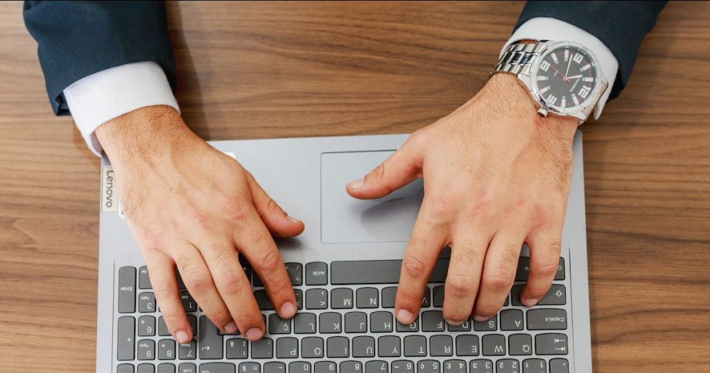 A person types on a laptop at a desk.