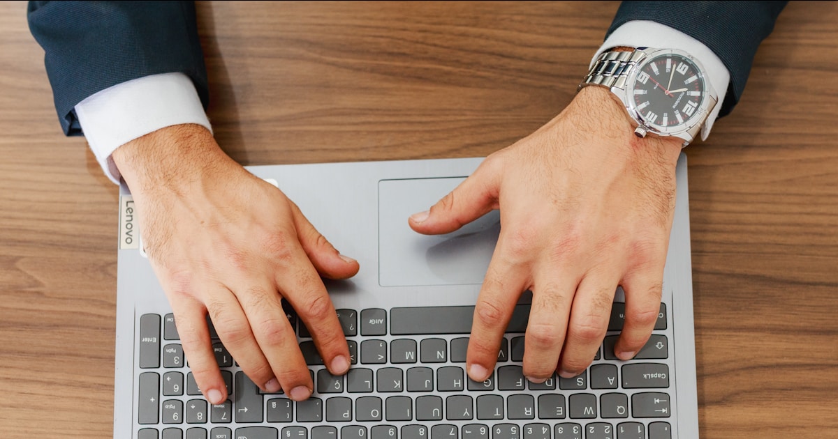 A person types on a laptop at a desk.