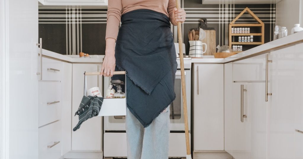 a woman standing in a kitchen holding a broom