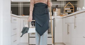 a woman standing in a kitchen holding a broom
