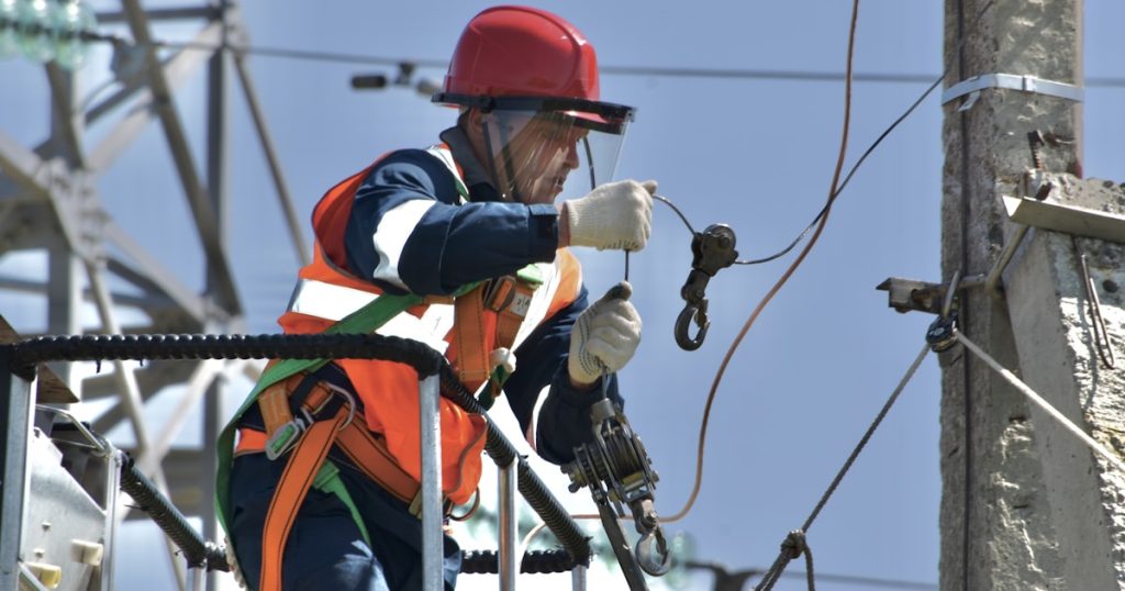 a man in safety gear working on a power pole