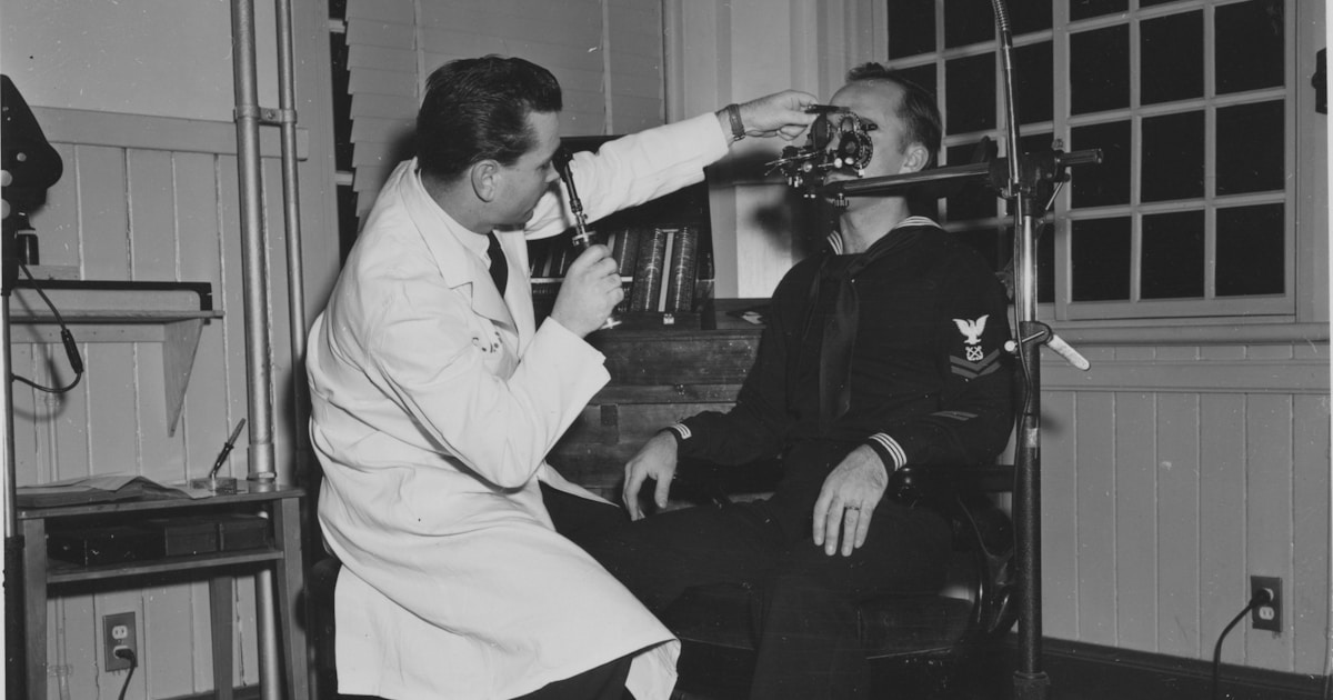 Doctor examines patient's eye with equipment.