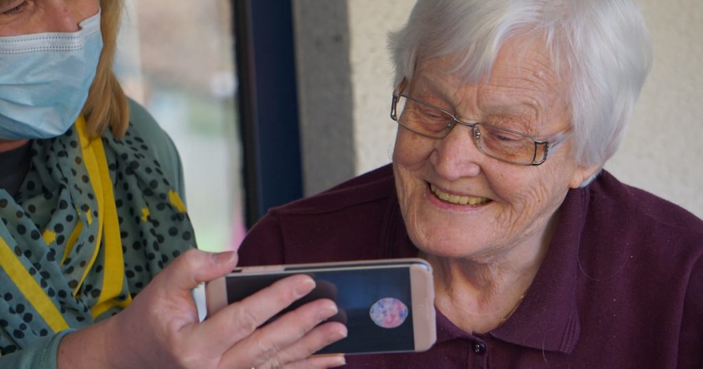 woman in brown button up shirt holding white smartphone