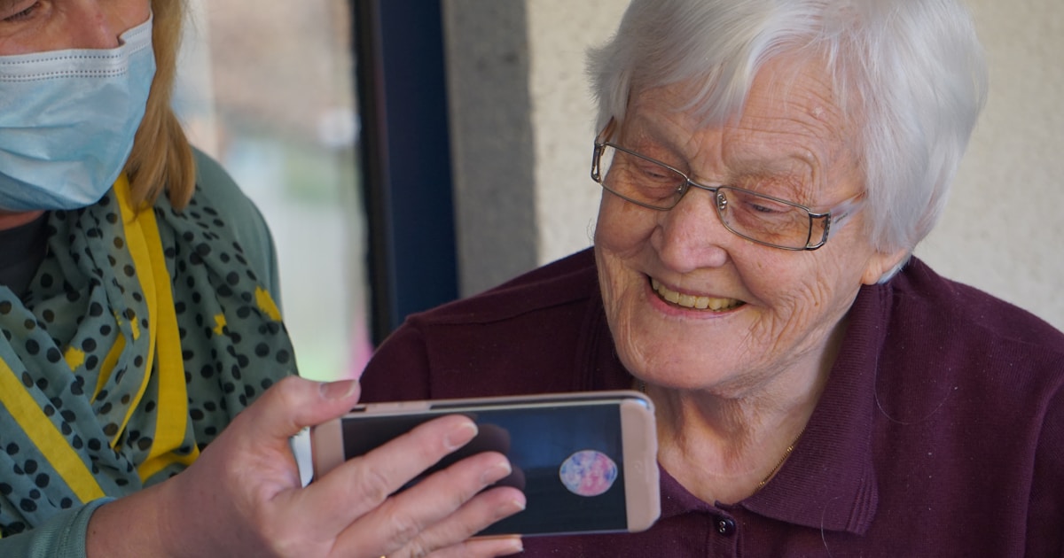 woman in brown button up shirt holding white smartphone