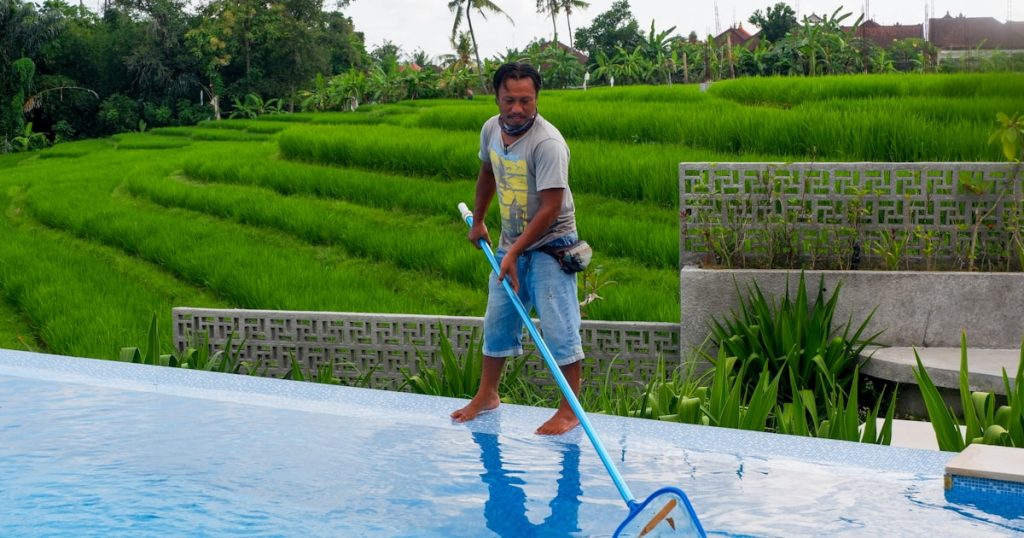 man in white polo shirt and blue denim jeans standing on swimming pool during daytime