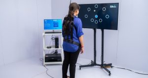 Woman stands on pressure plate with sensors on-screen interactive game.