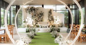 A wedding ceremony with a green carpet and white flowers