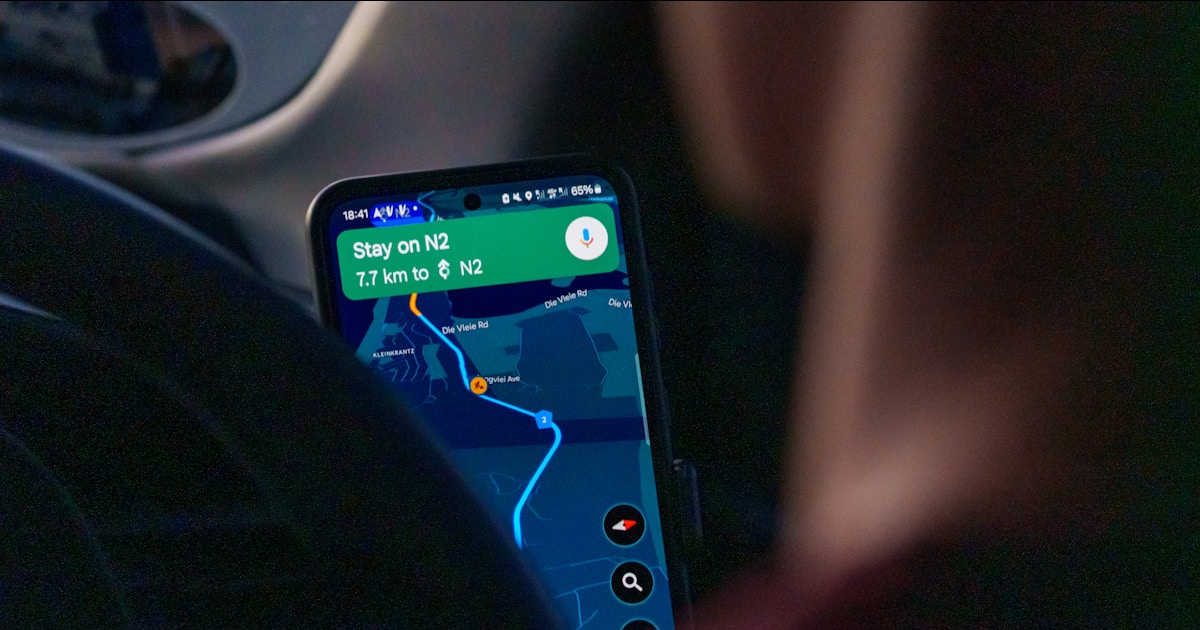 Person using navigation app on smartphone inside car.
