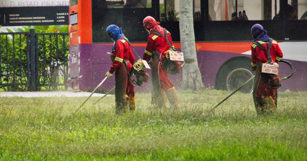 man in red jacket holding a stick near red bus during daytime
