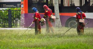 man in red jacket holding a stick near red bus during daytime