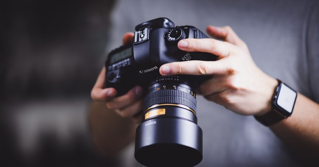 person holding Canon DSLR camera