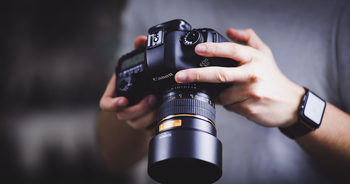 person holding Canon DSLR camera