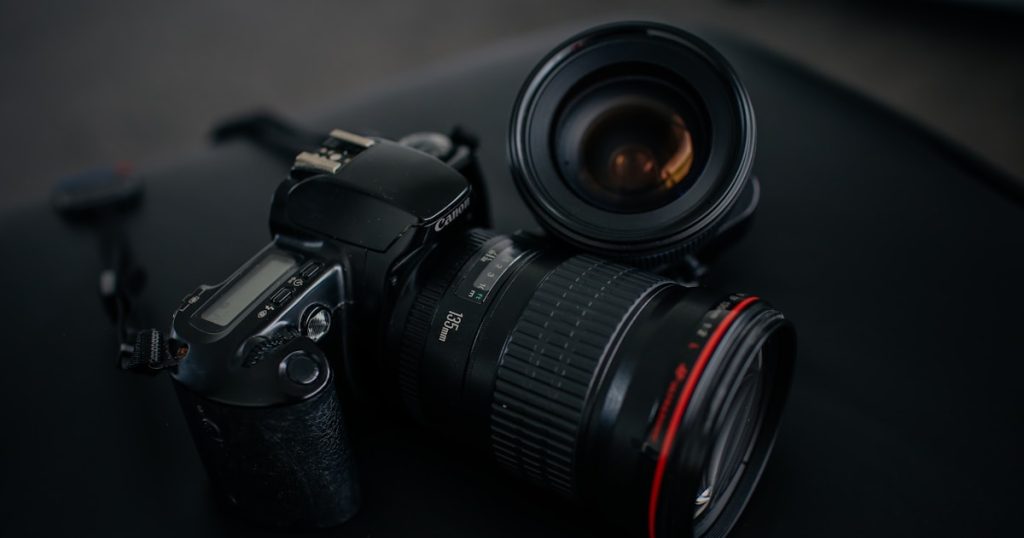 black Canon DSLR camera beside camera lens